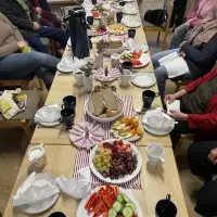 Die Frühstückstafel ist gedeckt. Die Gäste haben Platz genommen.